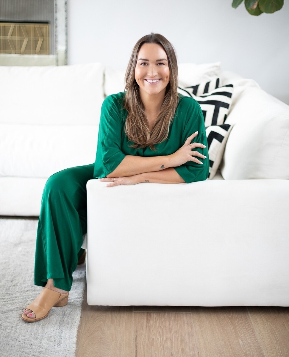 Brand Image of beautiful realtor in green outfit, leaning on white sofa