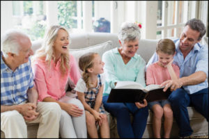 Multi-generation family looking at their album photo in living room